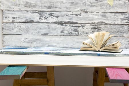 Composition with vintage old hardback books, diary, fanned pages on wooden deck table and red...