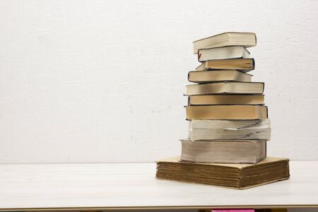 Composition with vintage old hardback books, diary, fanned pages on wooden deck table and red...