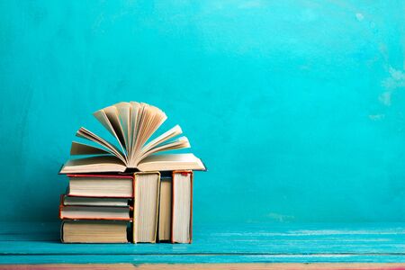 Composition with vintage old hardback books, diary, fanned pages on wooden deck table and red background. Books stacking. Back to school. Copy Space. Education background.の写真素材