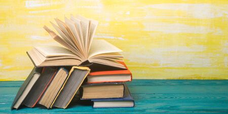 Composition with vintage old hardback books, diary, fanned pages on wooden deck table and red background. Books stacking. Back to school. Copy Space. Education backgroundの写真素材