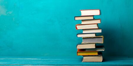 Composition with vintage old hardback books, diary, fanned pages on wooden deck table and red background. Books stacking. Back to school. Copy Space. Education background.の写真素材
