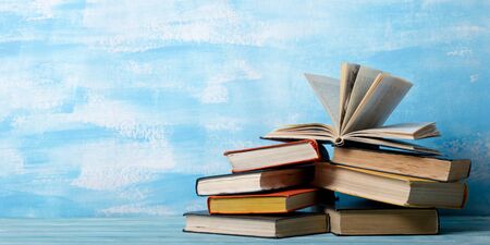 Composition with vintage old hardback books, diary, fanned pages on wooden deck table and red background. Books stacking. Back to school. Copy Space. Education backgroundの写真素材