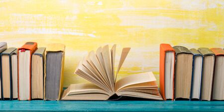 Composition with vintage old hardback books, diary, fanned pages on wooden deck table and red background. Books stacking. Back to school. Copy Space. Education backgroundの写真素材