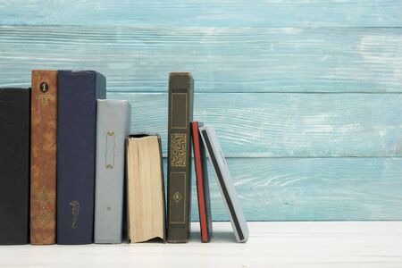 Composition with vintage old hardback books, diary, fanned pages on wooden deck table and red background. Books stacking. Back to school. Copy Space. Education backgroundの写真素材
