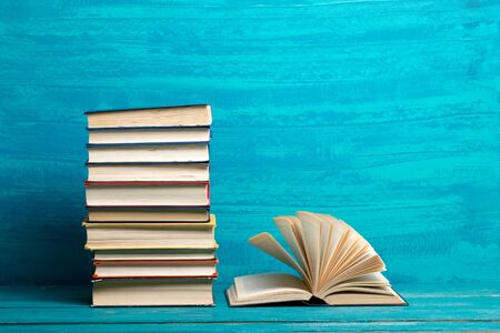 Composition with vintage old hardback books, diary, fanned pages on wooden deck table and red background. Books stacking. Back to school. Copy Space. Education backgroundの写真素材