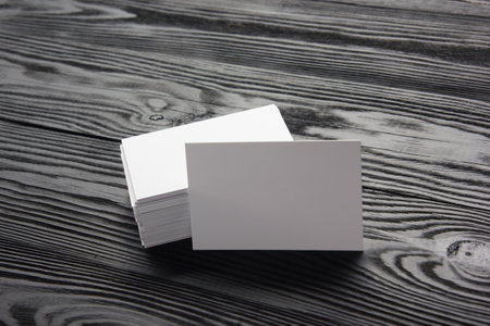 Business card blank on black wooden background. Corporate Stationery, Branding Mock-up. Creative designer desk. Flat lay. Copy space for textの写真素材