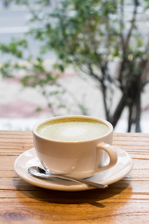 Close up hot green tea in a cup on wooden tableの写真素材