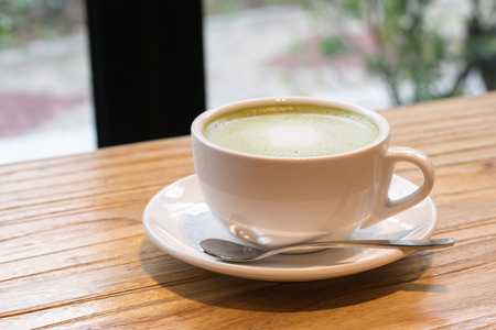 Close up hot green tea in a cup on wooden tableの写真素材