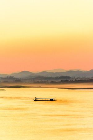Passenger ship on the Mekong river in the evening with fog and mountains background.の写真素材