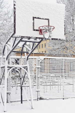 Snow covered basketball playground. Snow covered basketball hoopの写真素材