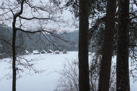 Historical peasant huts snowy winter forest in the meadow in winterの写真素材
