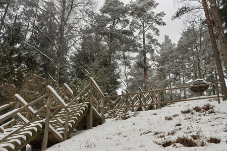 Snow-covered tourist wooden stairs in a forest in winter, without peopleの写真素材