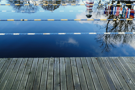 outdoor sports pool for winter swimming, wooden board edge, national flags on water reflection, The Sunrise Sky,  extreme outdoor activityの写真素材