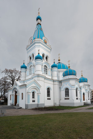 St. Simeon and St. Anne Orthodox Church on the edge of a street in the Latvian city of Jelgava during a snowfall. The photograph shows the domes of the church, a fence and trees in front.の写真素材