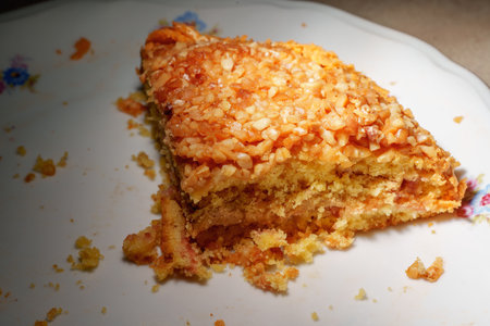 a delicious slice of nut cake on a white plate. the dessert is topped with golden, chopped nuts, creating a cozy and mouth-watering sceneの写真素材
