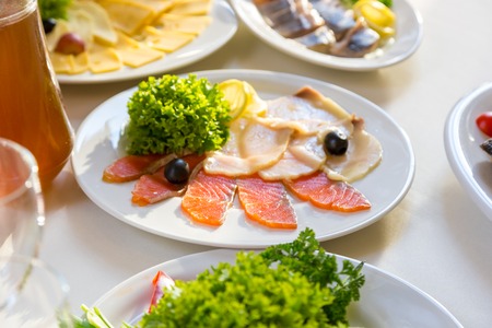 Red fish sliced on a plate. Sliced red fish salmon greens lemon black olives on plateの写真素材