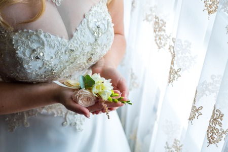 Bride holding a buttonhole. Gentle hand of the bride holding boutonniere for the groomの写真素材