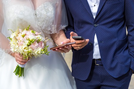 the bride and groom with mobile in hand. Modern wedding with gadgetsの写真素材