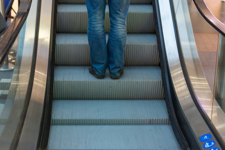 Girl wear sneaker riding on an escalator. feet standing on escalatorの写真素材
