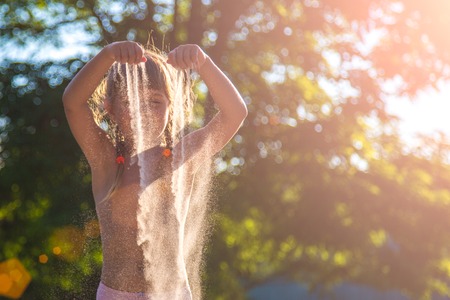 Young girl with sand in hands. Sand is wrapped in the sunsetの写真素材