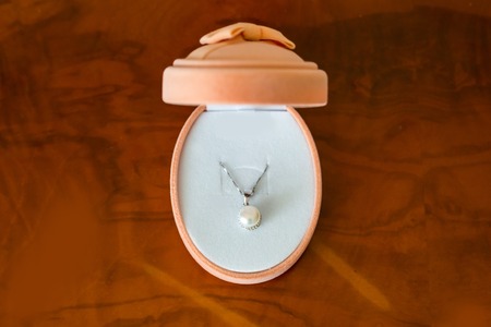 White necklace in an orange box on the table. Festive giftの写真素材