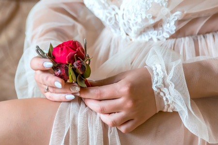 Bride holding a buttonhole. Gentle hand of the bride holding boutonniere for the groomの写真素材