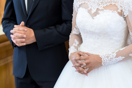 Unrecognizable bride and groom in the church during the Christian wedding ceremony. Hands of brides close up in the churchの写真素材