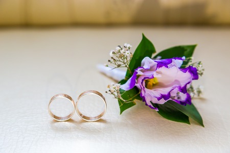 Wedding rings lie next to the wedding bottle of purple flowersの写真素材