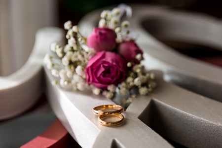 Wedding rings are lying on white paper carved into a pattern.の写真素材