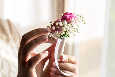 Bride holding a buttonhole. Gentle hand of the bride holding boutonniere for the groomの写真素材