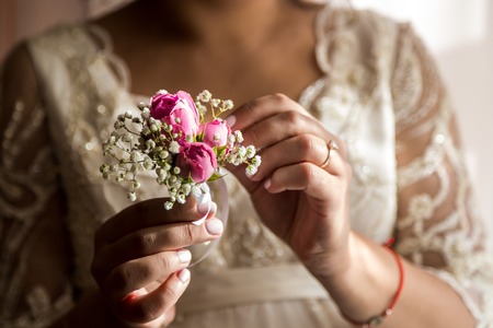 Bride holding a buttonhole. Gentle hand of the bride holding boutonniere for the groomの写真素材