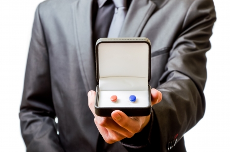 A business man offers to take the red pill or the blue pillの写真素材