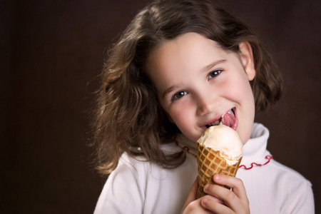 Beautiful young girl licking an ice cream coneの写真素材