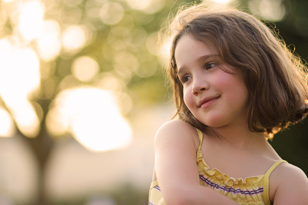 Young girl smiling on a sunny day with beautiful bokeh backgroundの写真素材