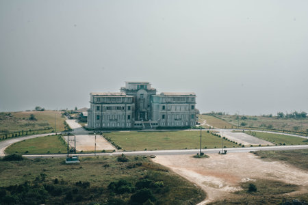 Abandoned hospital in the middle of the field with a cloudy skyの写真素材