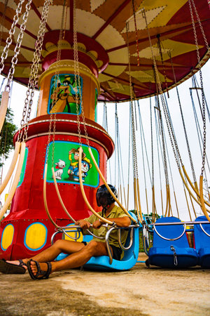 Guy with a motorcycle helmet (daftpunk like) on flying chairs in an abandoned amusement park, in the Pakse loop, Laos.の写真素材
