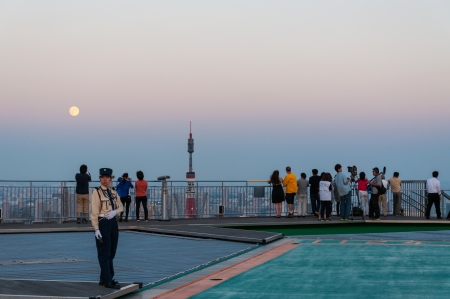 Photographers and tourists look out over the Tokyo cityscape from the roof of a skyscraper. The top of Tokyo Tower is just visible in the background.のeditorial素材