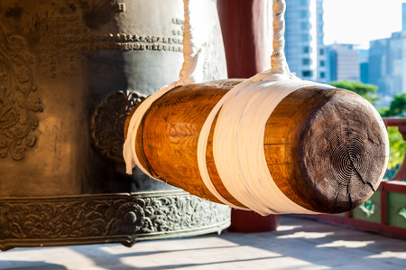 A large wooden ram hangs still beside an enormous iron bell at Bongeunsa Temple in Seoul, South Korea.の写真素材