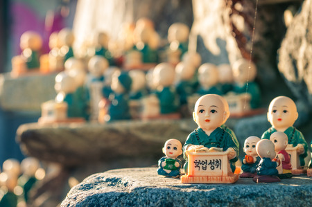 Little figurines scattered around the rocks of Haedong Yonggungsa Temple in Busan, South Korea. The figurines are meant to encourage academic achievement.の写真素材