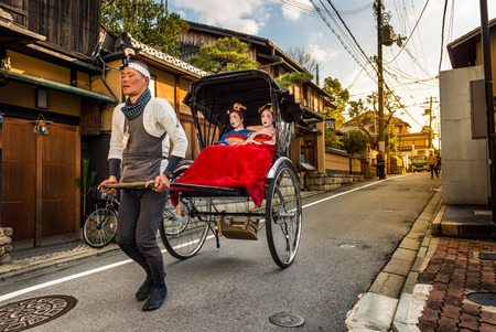 Geishas ride in the back of a rickshaw through the Gion district on December 29, 2015 in Kyoto, Japan.のeditorial素材