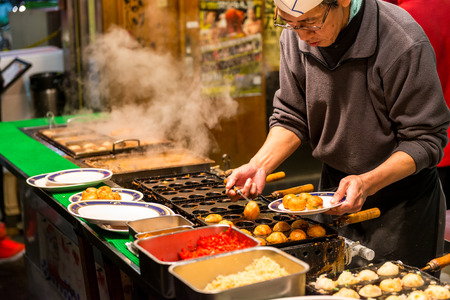 A Japanese man grills takoyaki at a food stall on December 27, 2014 in Osaka, Japan.のeditorial素材