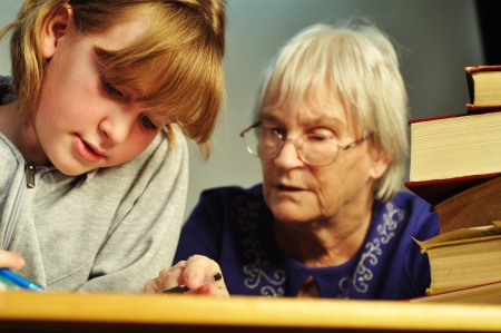 A senior woman helping a girl with her homeworkの写真素材