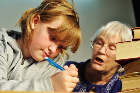 A senior woman helping a girl with her homeworkの写真素材