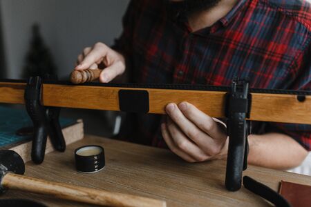 Man hands smoothing the leather with the special instrument. Leather craft. Handmade