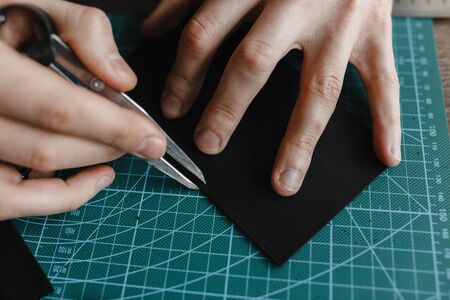 Man hands with special instrument for making wallet from the leather. Close up. Handmade...