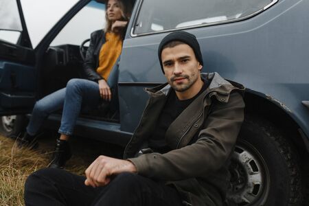 Man in the black hat sitting near his car. Woman portrait