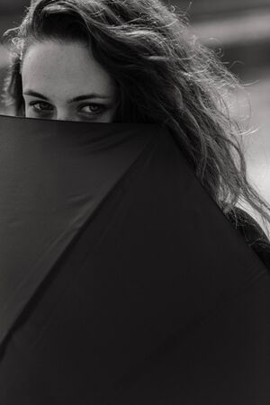 Closeup portrait of the woman looking out of the umbrella. Woman portraitの写真素材