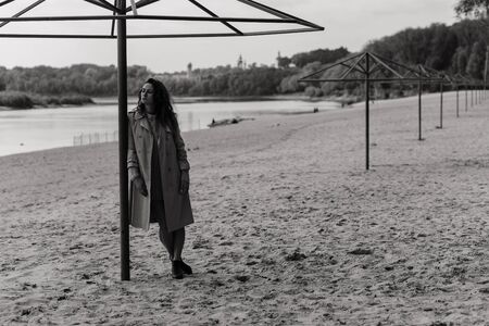 Woman in the coat standing near the metal construction on the river bank. Woman portraitの写真素材
