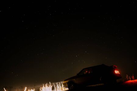 Car with headlights on starry sky background. Night skyの写真素材