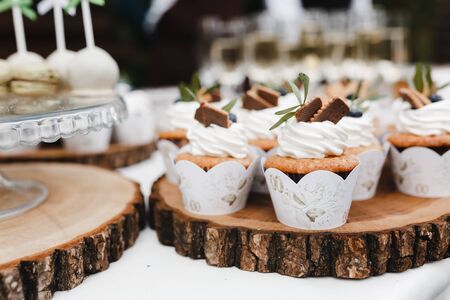 Vanilla cupcakes decorated with cream and berries on wooden place. Wedding cupcakes. Dessert